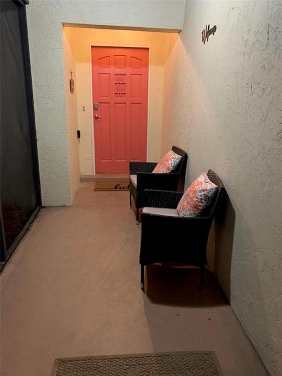 A covered entryway features a coral-colored front door, two wicker chairs, and textured walls — 132 HALLMARK AVENUE, LAKE PLACID, FL