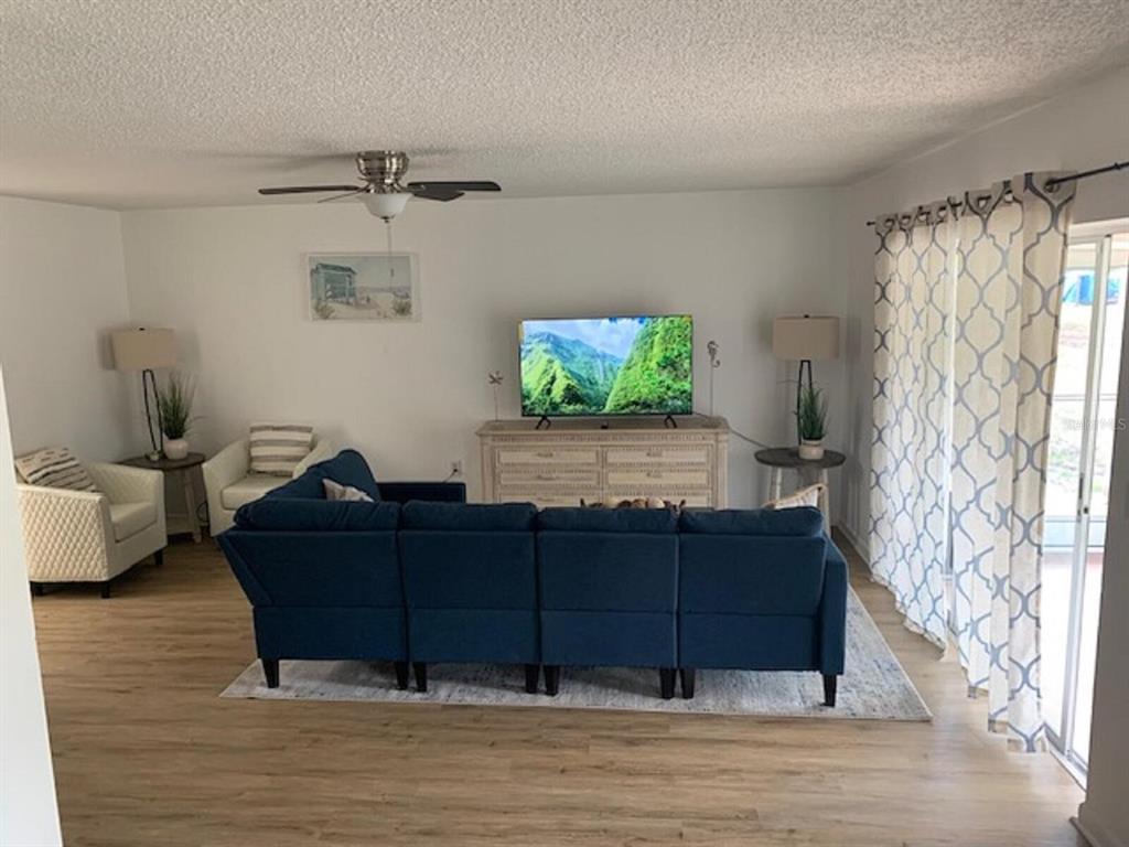 A living room features a blue sectional sofa, a television on a dresser, and curtains — 132 HALLMARK AVENUE, LAKE PLACID, FL