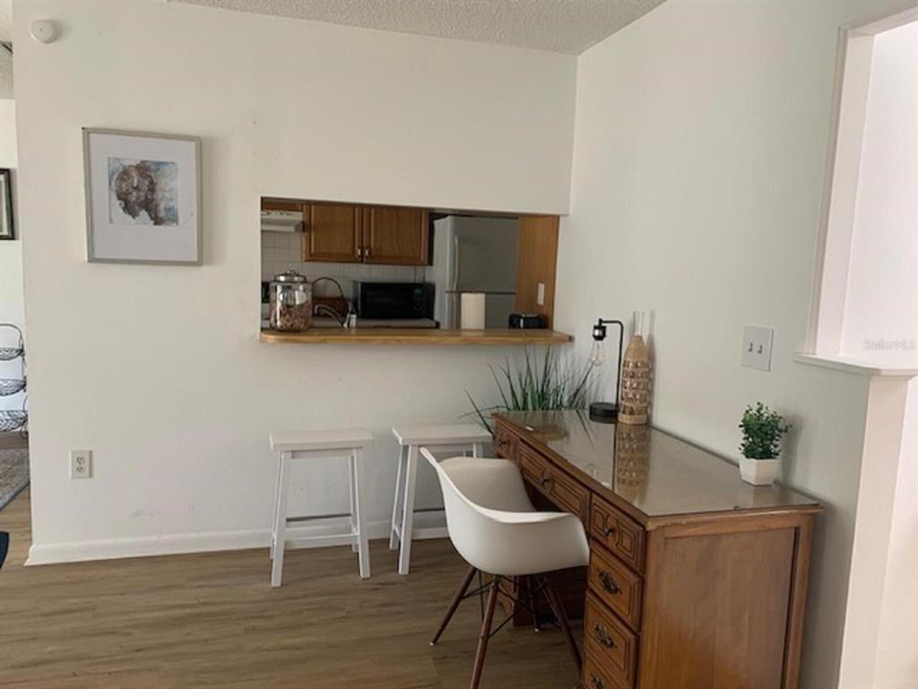 A room features a kitchen pass-through window, a wooden desk, and two white bar stools — 132 HALLMARK AVENUE, LAKE PLACID, FL