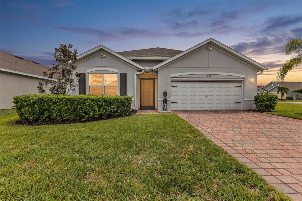 A single-story house with a gray stucco exterior, a paved driveway, and a manicured hedge — 4195 MANATEE LANE, PUNTA GORDA, FL