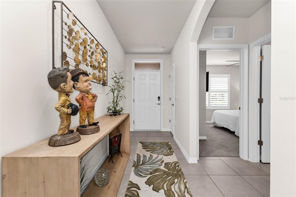 A bright entryway features a wooden console table with Laurel and Hardy figurines and tile flooring — 4195 MANATEE LANE, PUNTA GORDA, FL