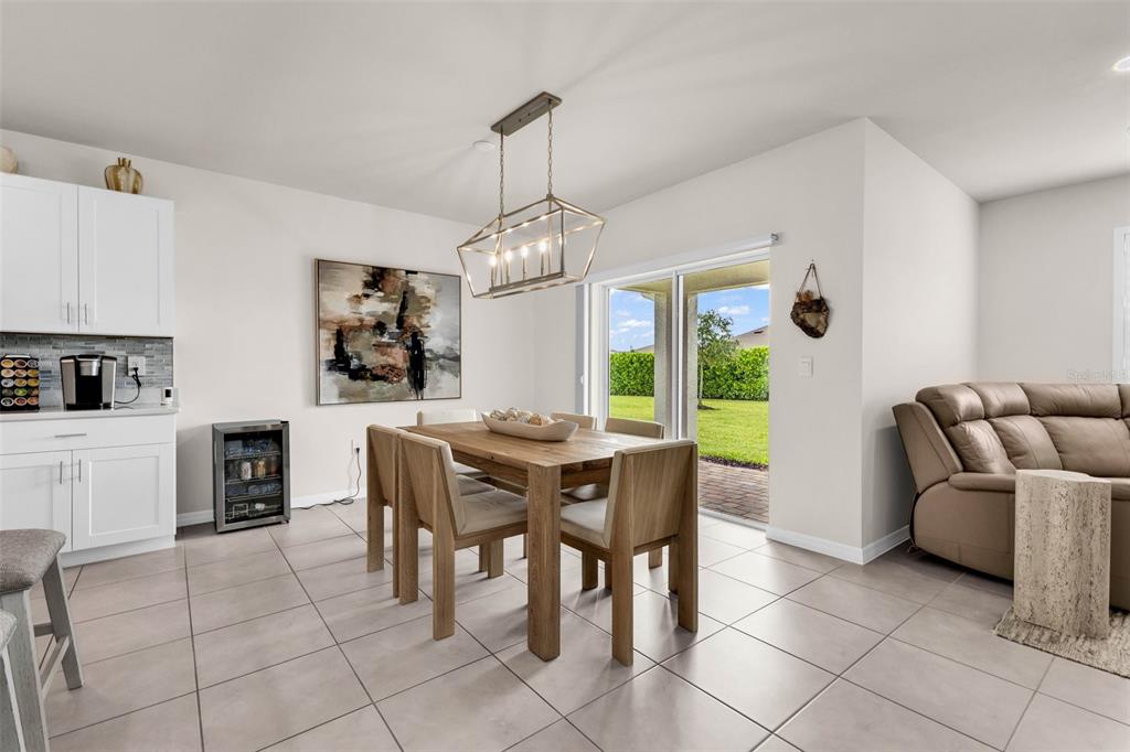 A dining area features a wooden table, modern chandelier, tile flooring, and sliding glass doors — 4195 MANATEE LANE, PUNTA GORDA, FL