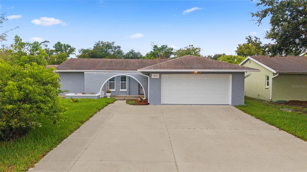 A single-story house with a gray stucco exterior, a two-car garage, and an arched entryway — 5019 LARCH LANE, NEW PORT RICHEY, FL