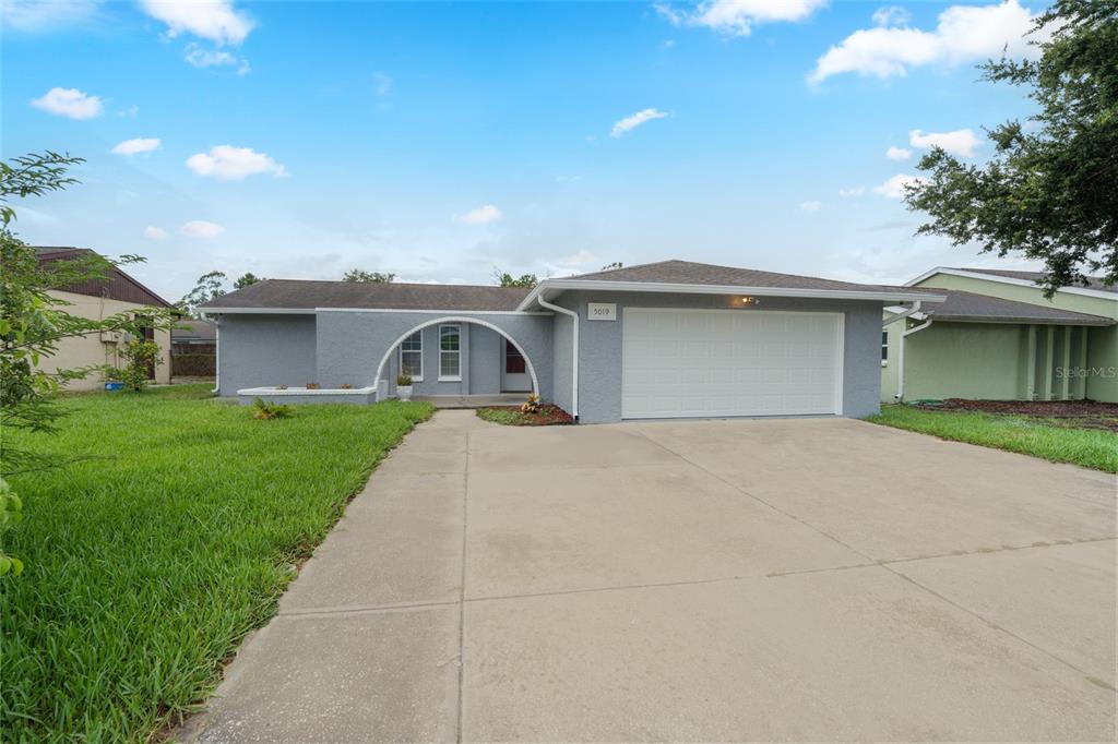 A single-story gray house with a prominent arched entryway and a two-car garage — 5019 LARCH LANE, NEW PORT RICHEY, FL