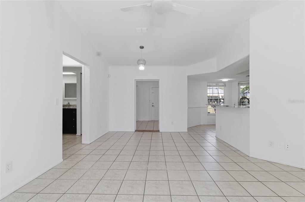 An open-concept room with white walls, light-colored tile flooring, a ceiling fan, and a kitchen — 5019 LARCH LANE, NEW PORT RICHEY, FL