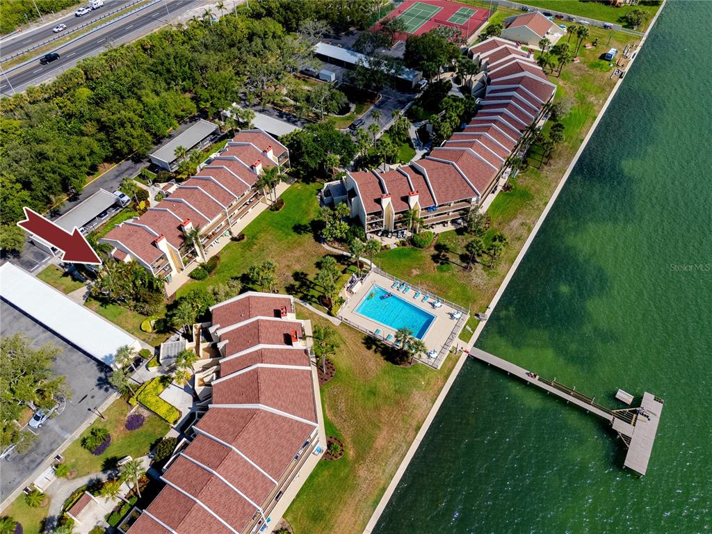 An aerial view shows multi-story residential buildings, a swimming pool, and a dock by water — 7510 SUNSHINE SKYWAY LANE S UNIT P4, ST PETERSBURG, FL