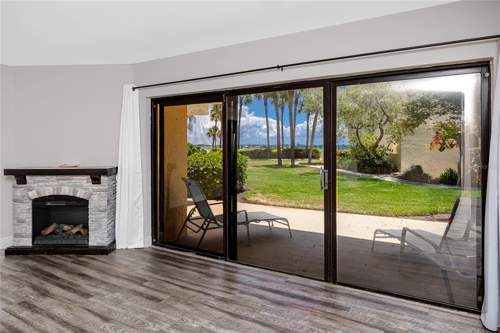 A living room features a stone fireplace, wood-look flooring, and sliding glass doors to a patio — 7510 SUNSHINE SKYWAY LANE S UNIT P4, ST PETERSBURG, FL