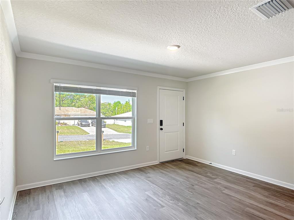 A room with light gray walls, wood-look flooring, a window, and an exterior door — 6040 W OAK PARK BOULEVARD, HOMOSASSA, FL