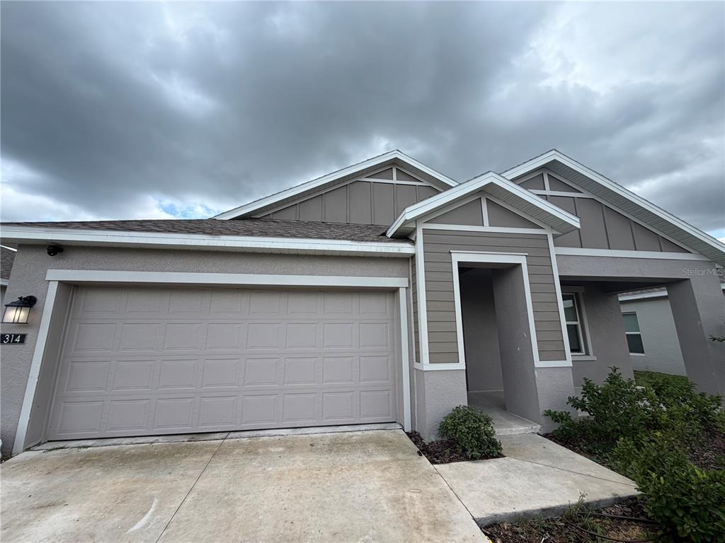 The exterior of a single-story house features a two-car garage and a covered entryway — 314 LAWSON AVENUE, HAINES CITY, FL