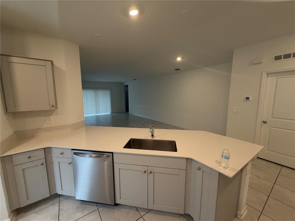 A kitchen with light gray cabinets, a stainless steel dishwasher, and a light-colored countertop — 314 LAWSON AVENUE, HAINES CITY, FL