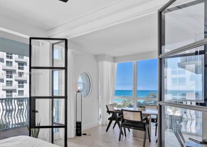 A bedroom with black-framed glass doors opens to a dining area overlooking the ocean — 1500 Ocean Dr # 607, Miami Beach FL 33139, MIAMI BEACH, FL