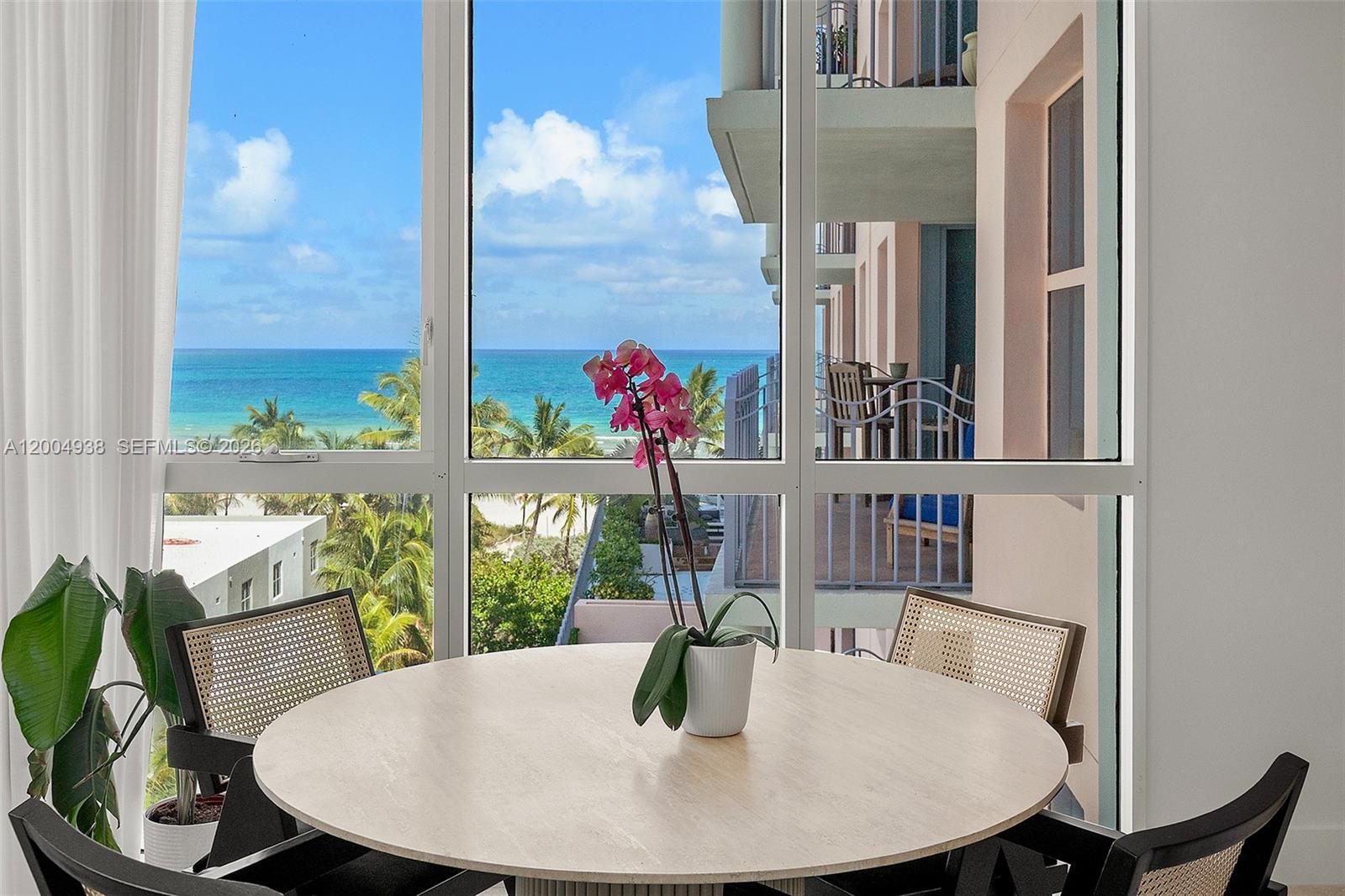 A round dining table with an orchid sits before large windows overlooking the ocean — 1500 Ocean Dr # 607, Miami Beach FL 33139, MIAMI BEACH, FL