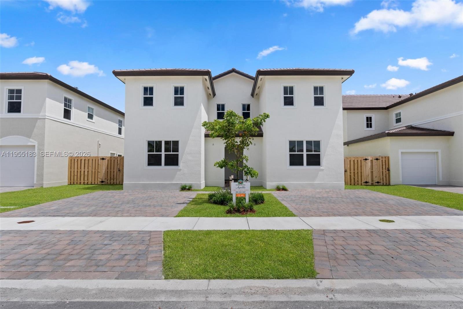 A two-story duplex with white stucco walls, a tiled roof, and paved driveways — 27333 SW 133rd Path, Homestead FL 33032, HOMESTEAD, FL