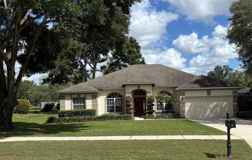 A single-story house with a beige stucco exterior, a red front door, and a garage — 561 STRATHCLYDE COURT, APOPKA, FL