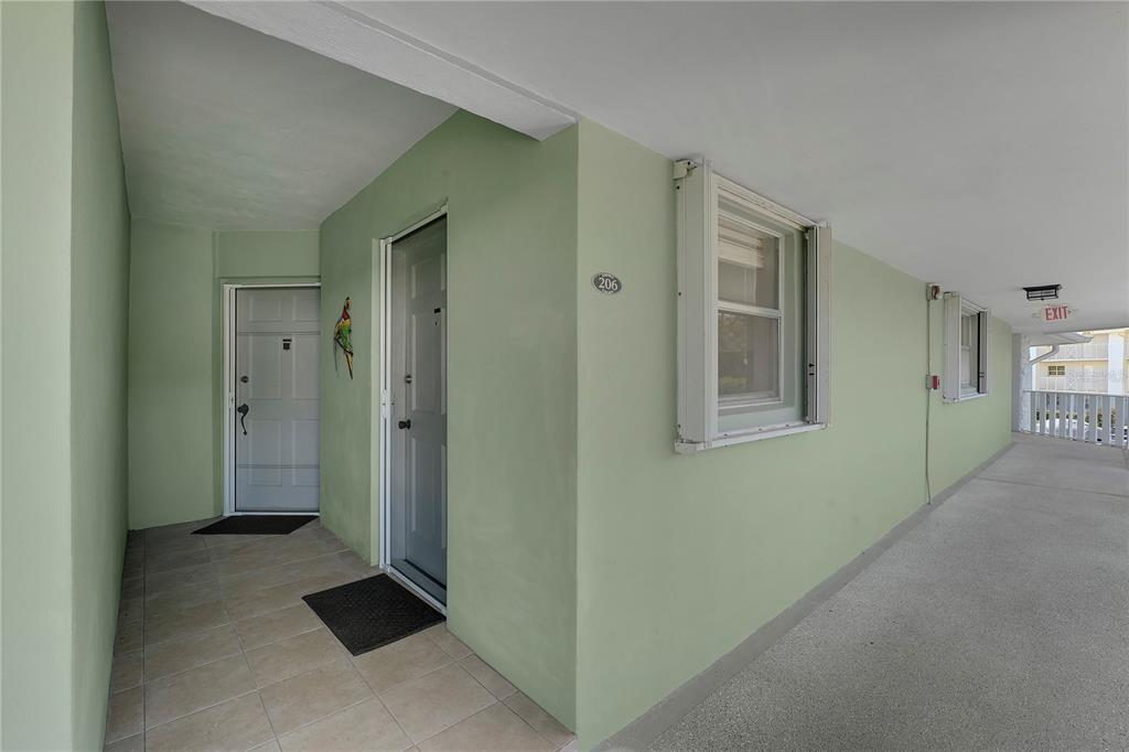 An exterior walkway leads to the entrance of unit 206 with light green walls — 5540 N OCEAN BOULEVARD UNIT 206, OCEAN RIDGE, FL