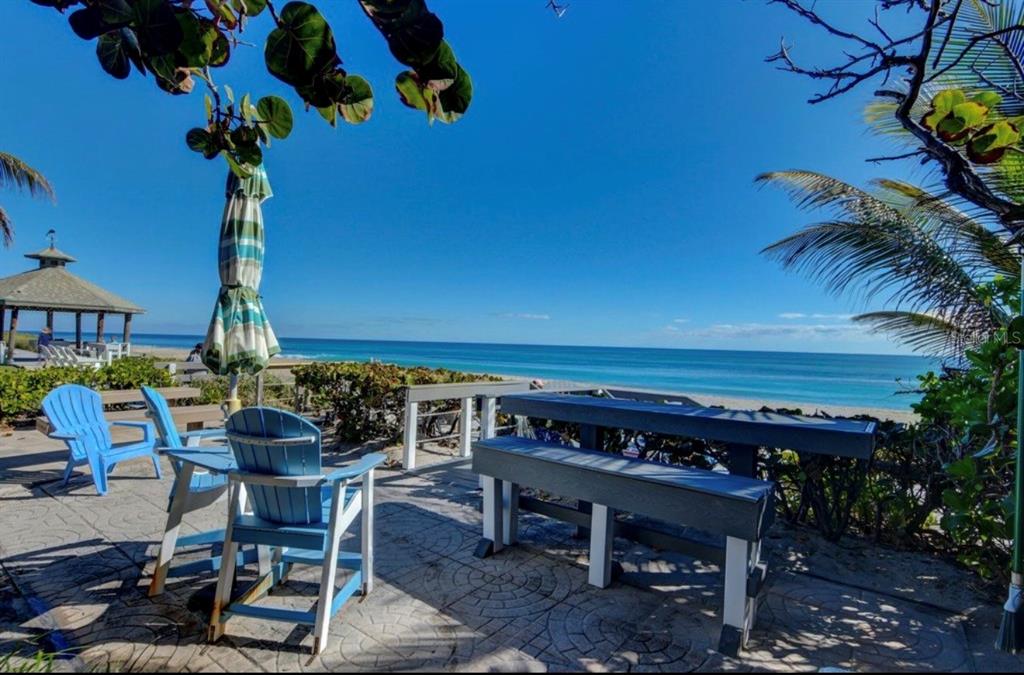 A patio with blue chairs and a picnic table overlooks a beach and the ocean — 5540 N OCEAN BOULEVARD UNIT 206, OCEAN RIDGE, FL