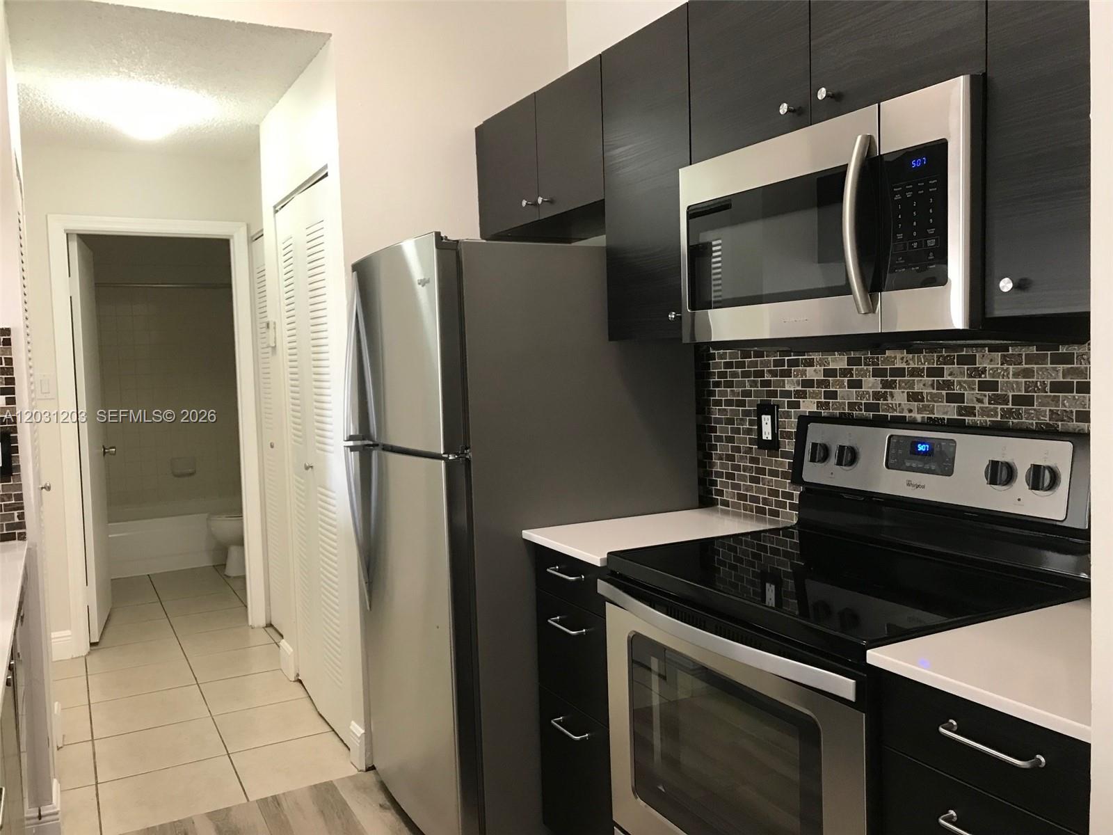 A kitchen features dark cabinets, stainless steel appliances, white countertops, and a tiled backsplash — 15780 SW 106th Ter # 306, Miami FL 33196, MIAMI, FL