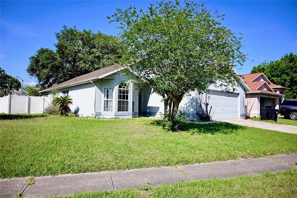 A single-story house with a light-colored exterior, a front-facing garage, and a large tree — 11534 KENLEY CIRCLE, ORLANDO, FL