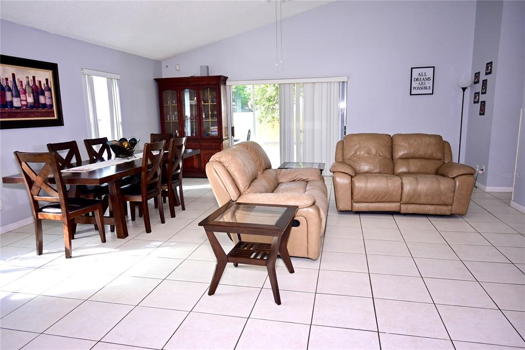 A dining area and living room with tan leather furniture and light-colored tile flooring — 11534 KENLEY CIRCLE, ORLANDO, FL
