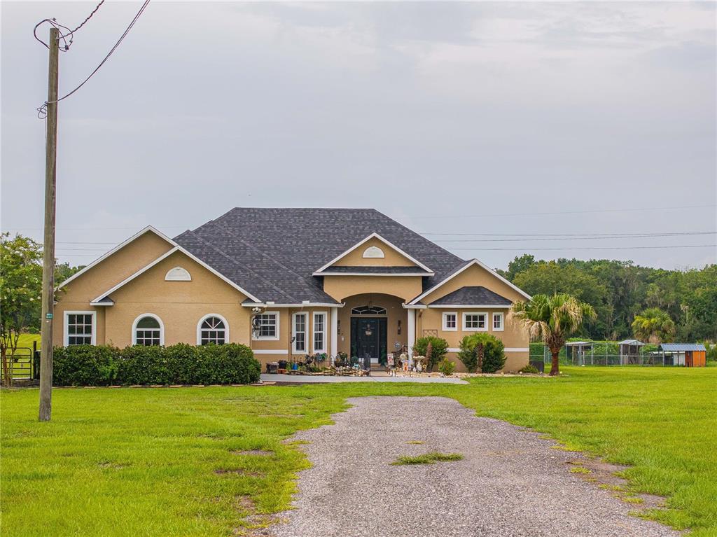 A single-story tan house with a dark shingled roof sits behind a gravel driveway — 4280 TURNER ROAD, MULBERRY, FL