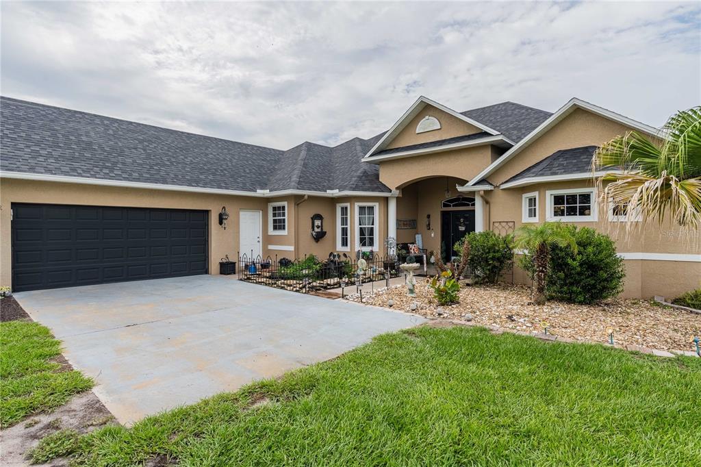 A tan single-story house with a dark garage door, shingled roof, and landscaped front yard — 4280 TURNER ROAD, MULBERRY, FL