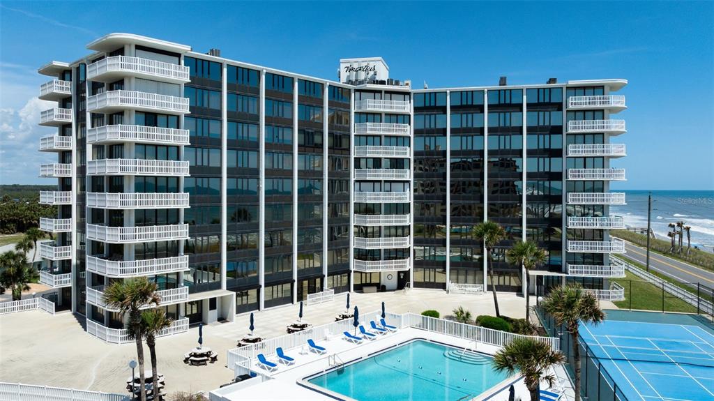 An aerial view of a multi-story beachfront condominium building with a pool and tennis court — 3580 S OCEAN SHORE BOULEVARD UNIT 910, FLAGLER BEACH, FL