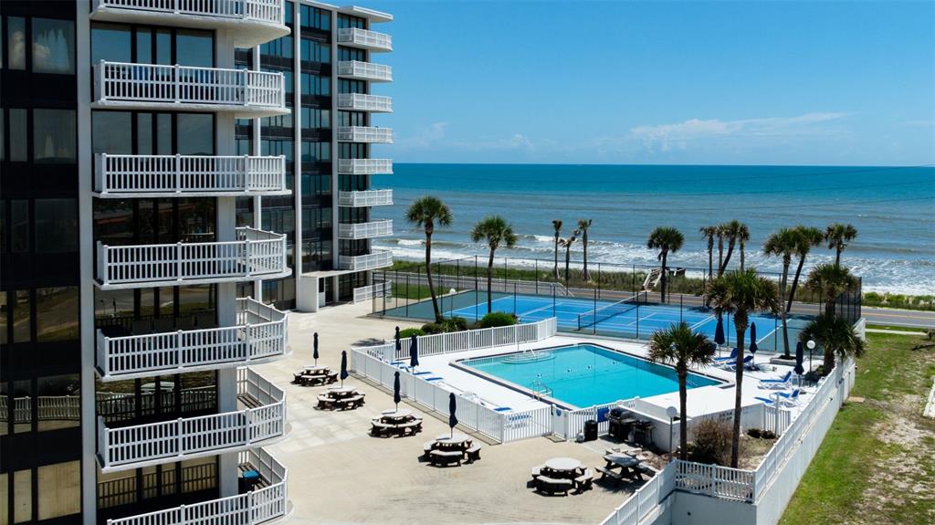 An aerial view of a multi-story building with balconies, a swimming pool, and tennis courts — 3580 S OCEAN SHORE BOULEVARD UNIT 910, FLAGLER BEACH, FL