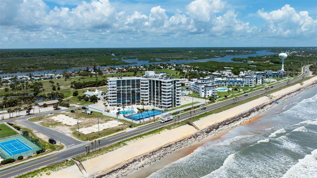 An aerial view shows a beachfront condominium complex with a pool and tennis courts — 3580 S OCEAN SHORE BOULEVARD UNIT 910, FLAGLER BEACH, FL