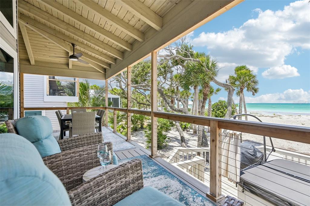 A covered wooden deck features outdoor furniture overlooking a sandy beach and the ocean — 6570 MANASOTA KEY ROAD, ENGLEWOOD, FL