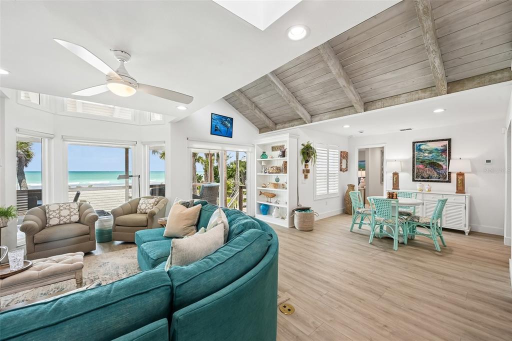 A bright living and dining area features a vaulted wood-beam ceiling and ocean views — 6570 MANASOTA KEY ROAD, ENGLEWOOD, FL