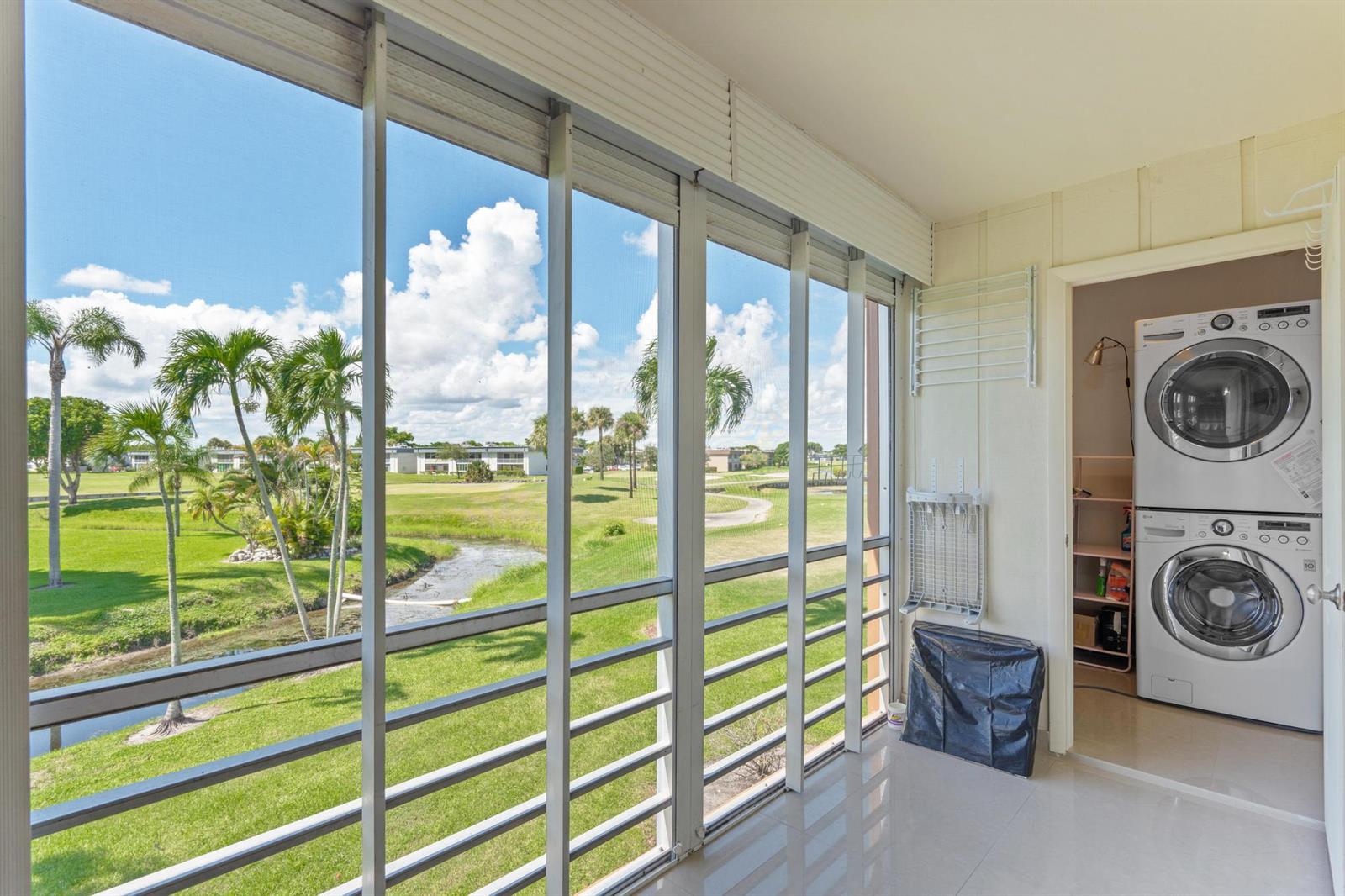 A screened-in balcony overlooks a golf course and features a stacked washer and dryer unit — 480 Flanders J, Delray Beach FL 33484, DELRAY BEACH, FL