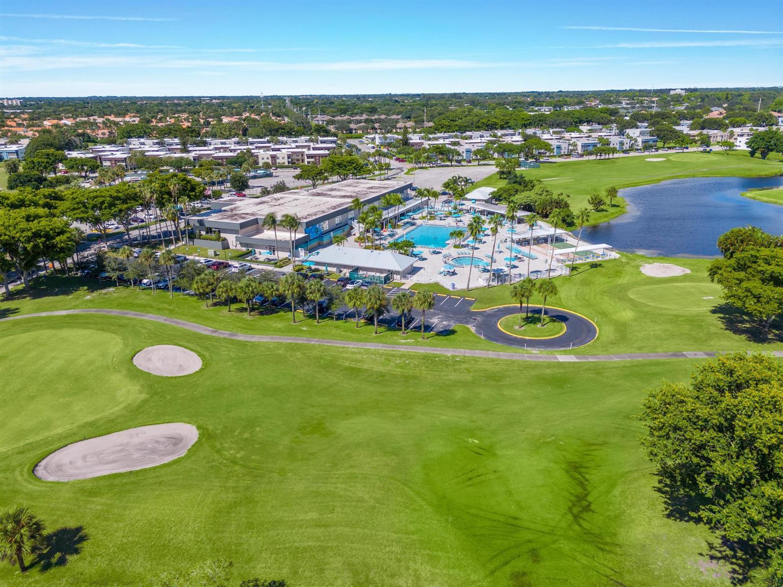 An aerial view shows a golf course, a swimming pool, and a large clubhouse building — 480 Flanders J, Delray Beach FL 33484, DELRAY BEACH, FL