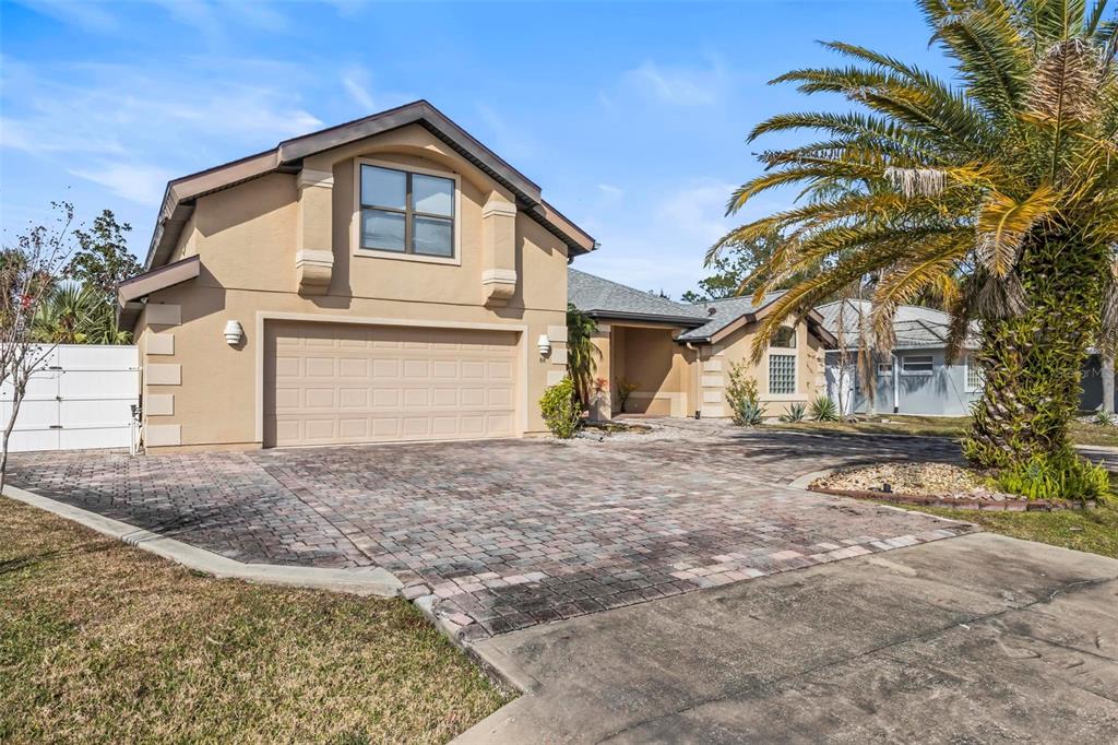 A tan two-story house features a paved driveway, a two-car garage, and a palm tree — 88 COVINGTON LANE, PALM COAST, FL
