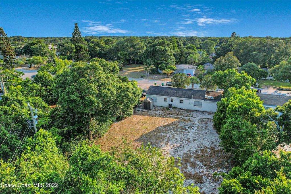 An aerial view shows a single-story house with a large, sandy backyard surrounded by trees — 1318 N FISKE BOULEVARD, COCOA, FL