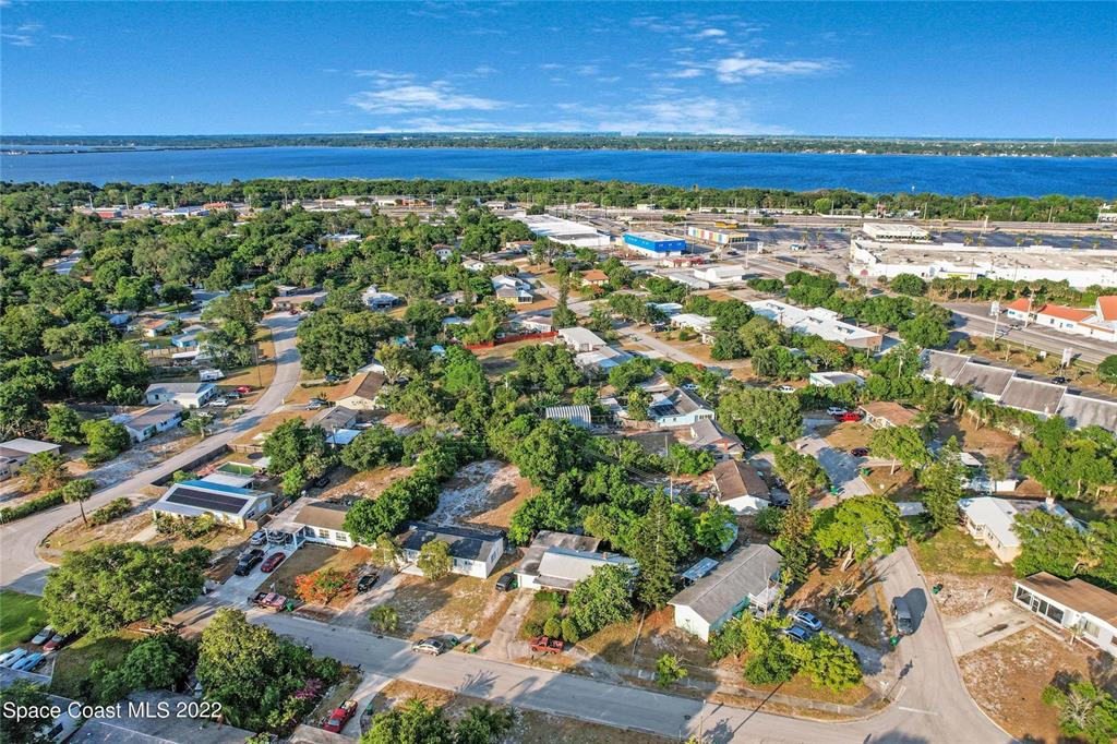 An aerial view shows a residential neighborhood with houses, trees, and a nearby body of water — 1318 N FISKE BOULEVARD, COCOA, FL