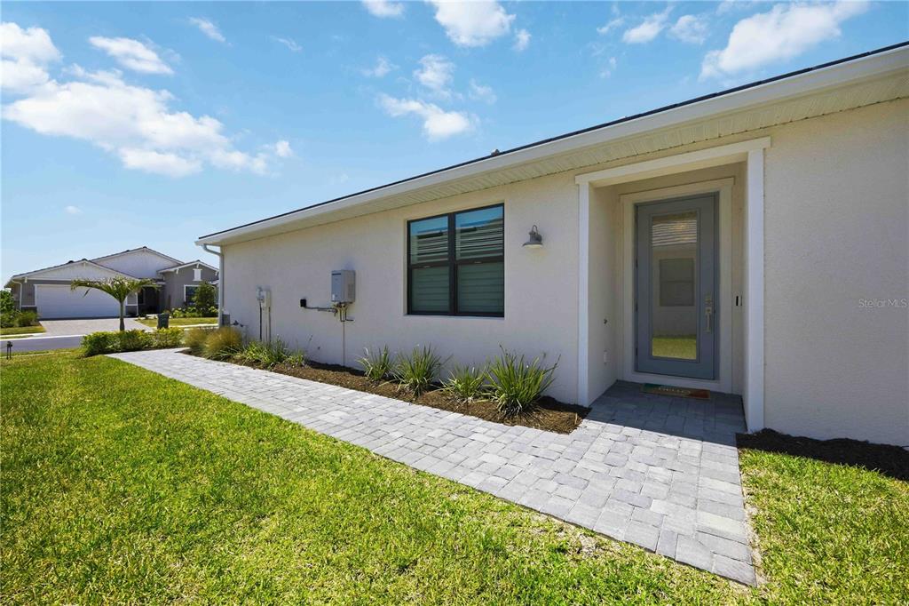 A screened-in patio with brick pavers overlooks a grassy field and natural landscape — 18652 DAYSPRING PLACE, VENICE, FL
