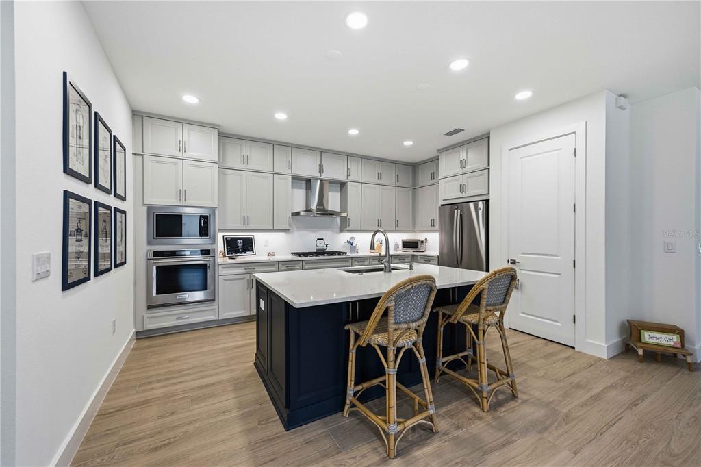 A modern bathroom features a double vanity, a glass-enclosed shower, and white marble-style flooring — 18652 DAYSPRING PLACE, VENICE, FL