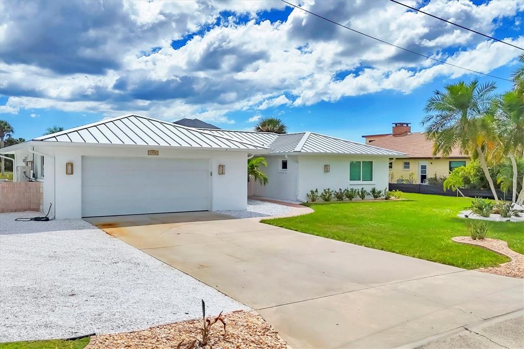 A white single-story house with a metal roof, a two-car garage, and a concrete driveway — 1915 PENNSYLVANIA AVENUE, ENGLEWOOD, FL