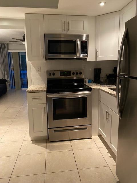 A kitchen features white cabinets, stainless steel appliances, and light-colored tile flooring — 209 SE 6th Street # 4, Boynton Beach FL 33435, BOYNTON BEACH, FL