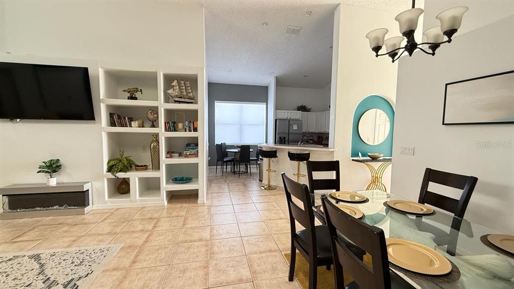 An open-concept living and dining area features tile floors, built-in shelving, and a kitchen pass-through — 2659 AUTUMN CREEK CIRCLE, KISSIMMEE, FL