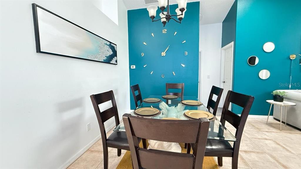 A dining room features a glass table, dark chairs, and a teal accent wall clock — 2659 AUTUMN CREEK CIRCLE, KISSIMMEE, FL