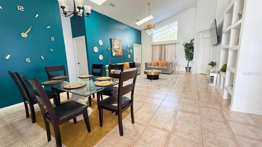 A dining area with a glass table and teal wall leads into a living room — 2659 AUTUMN CREEK CIRCLE, KISSIMMEE, FL