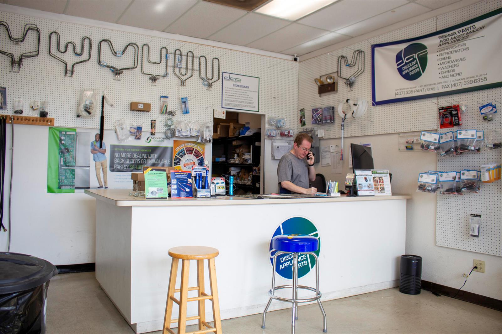 A man works behind the service counter of an appliance parts store with wall-mounted inventory — 851 W State Rt 436 # 1007, FL 32714, FL