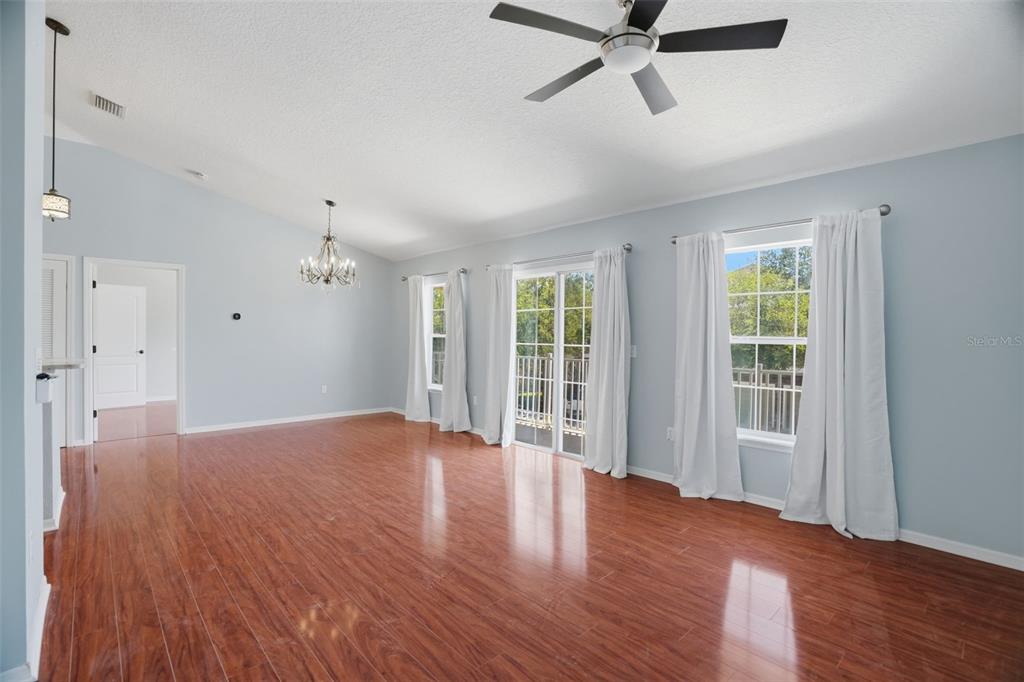 An empty living room features light blue walls, wood-look flooring, a ceiling fan, and sliding doors — 7001 INTERBAY BOULEVARD UNIT 151, TAMPA, FL