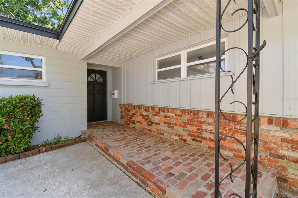 A covered brick porch leads to a black front door on a light gray house — 535 W PALMEDEN DRIVE, LAKELAND, FL