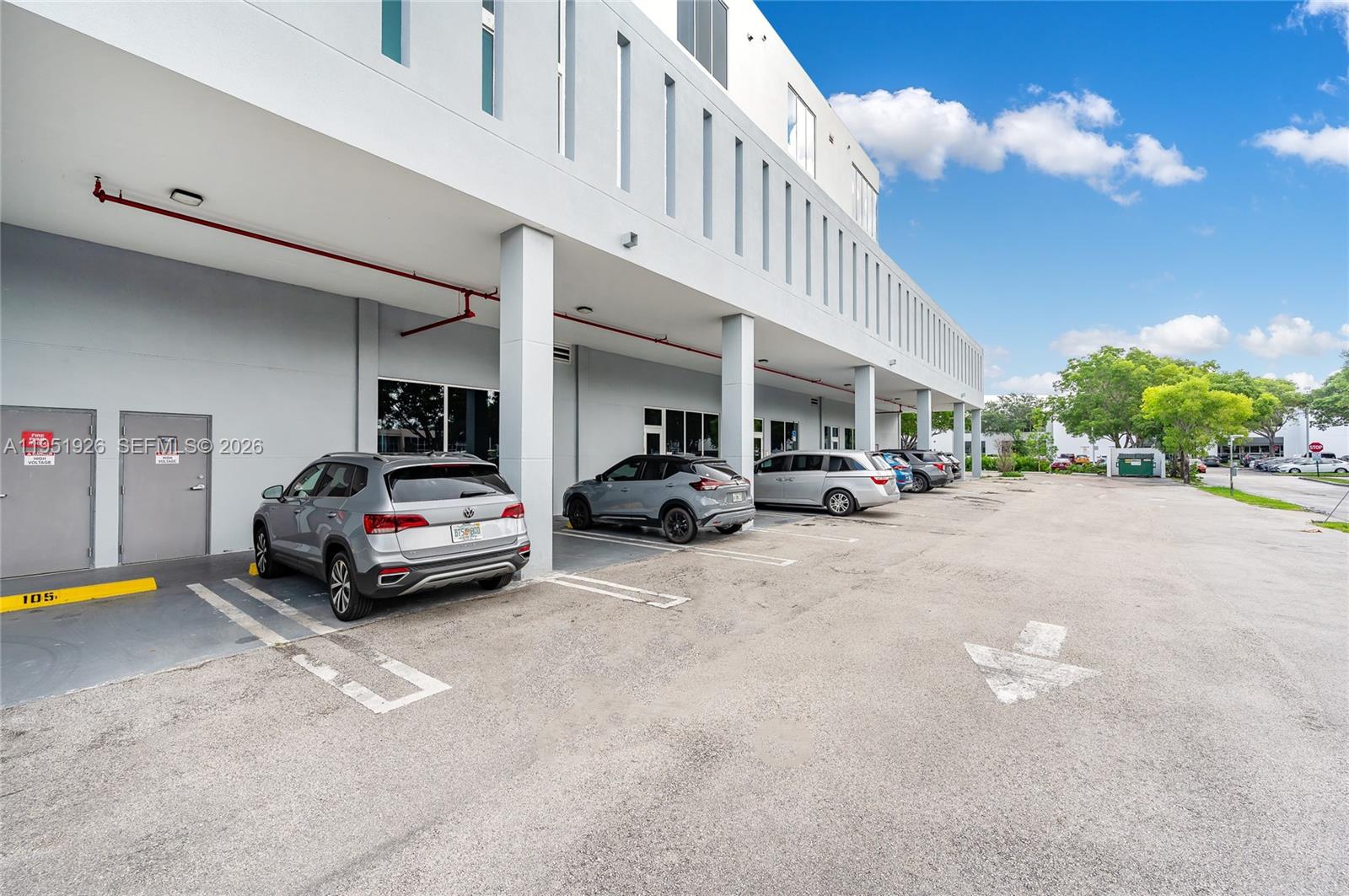 A row of parked cars sits under the covered overhang of a modern commercial building — 10450 NW 33rd St # 501, Doral FL 33172, DORAL, FL
