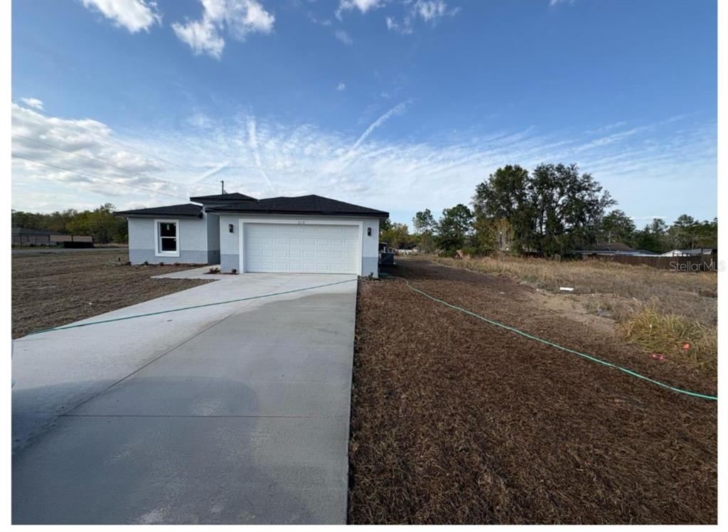 A single-story house with a white stucco exterior, gray brick base, and a two-car garage — 843 W GAGE LANE, DUNNELLON, FL