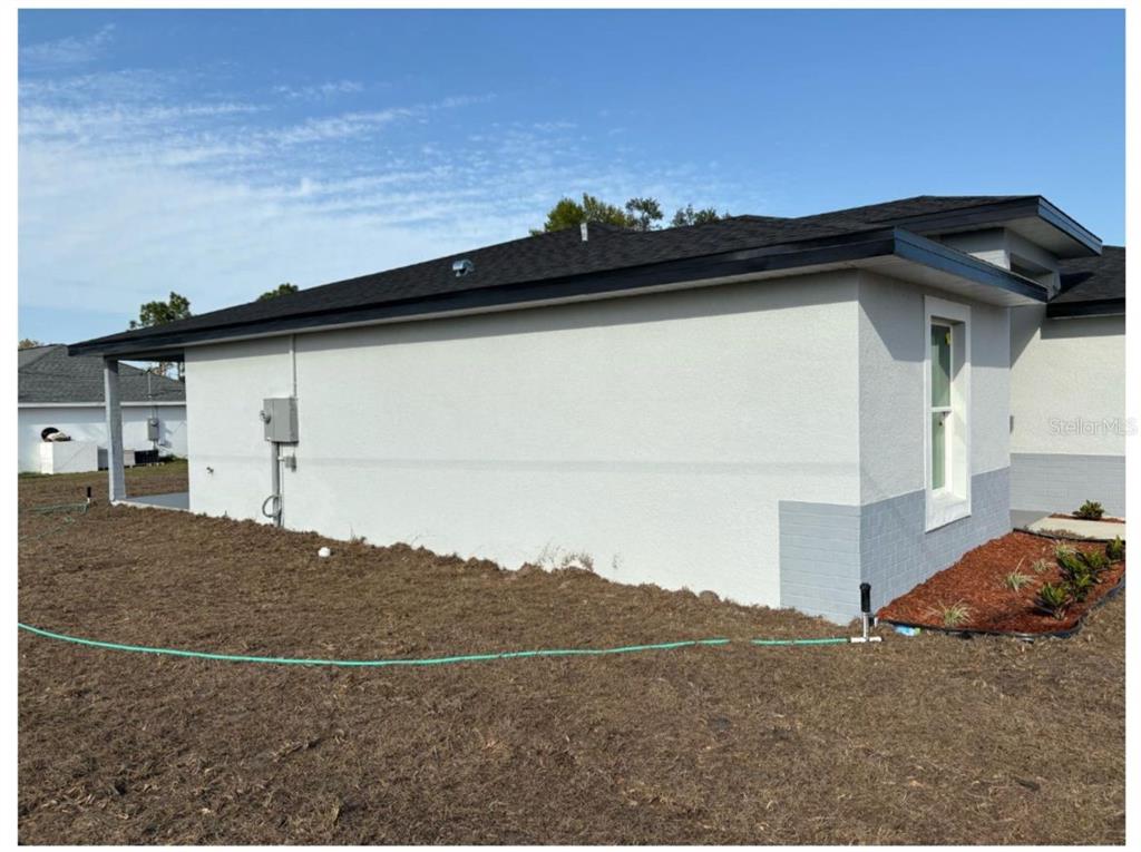 A single-story house with a white stucco facade, grey brick base, and a dark roof — 843 W GAGE LANE, DUNNELLON, FL