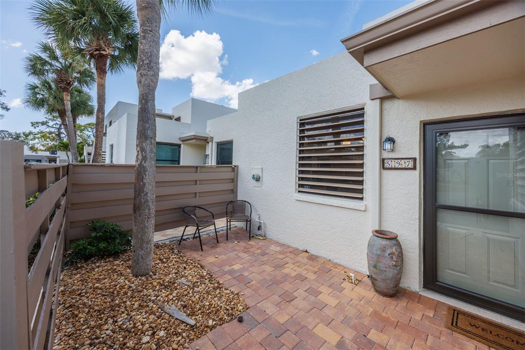 A paved patio area features two chairs, a large decorative pot, and a privacy fence — 597 LAKESIDE DRIVE UNIT 597, BRADENTON, FL