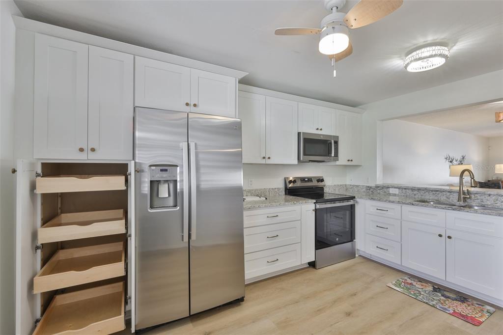 A kitchen with white cabinets, stainless steel appliances, granite countertops, and light wood-look flooring — 597 LAKESIDE DRIVE UNIT 597, BRADENTON, FL